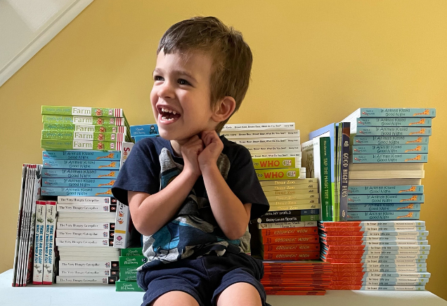 Child happily sitting on shelf full of books