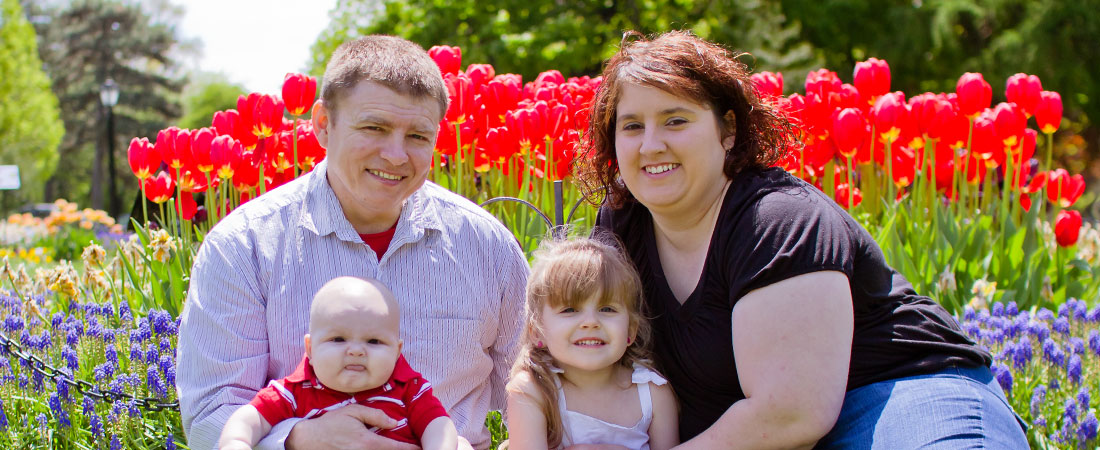Family of four sits in a park surrounded by tulips