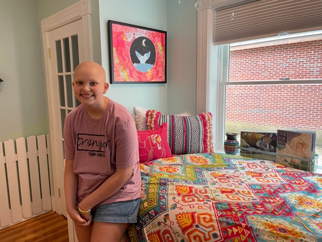 11-year-old Anna LaBella stands in a brightly decorated corner of the Ronald McDonald Family Retreat, where one of her original paintings hangs over the bed.