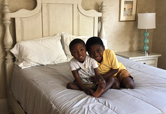 Brothers pose shoulder to shoulder on a bed at the Ronald McDonald House in Albany