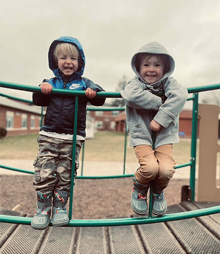 Two young boys laughing and playing on playground equipment