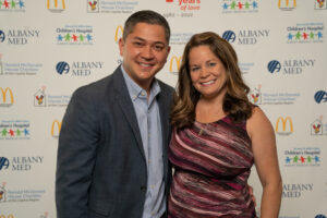 Stephen & Briana Sudarto pose in front of step and repeat backdrop at RMHC-CR 40 Years of Love Gala