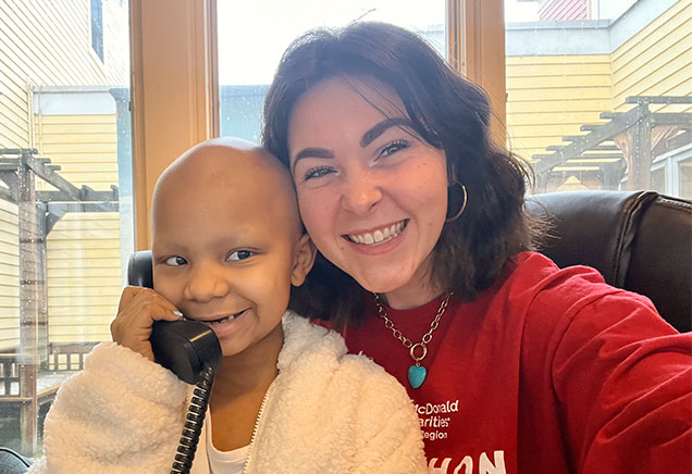 Little girl sitting on someone's lap and answering the phone while smiling at the Ronald McDonald House