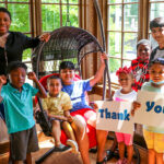 A group of eight children pose with a "Thank You" sign in the sunroom at the Albany Ronald McDonald House.