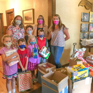 Three parents and five children pose with large collection of RMHC wish list items during drop off at the Ronald McDonald House