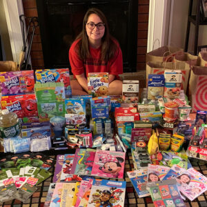 Teenage girl sits on floor surrounded by RMHC wish list items